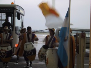 musicians in colorful outfits beside arriving bus